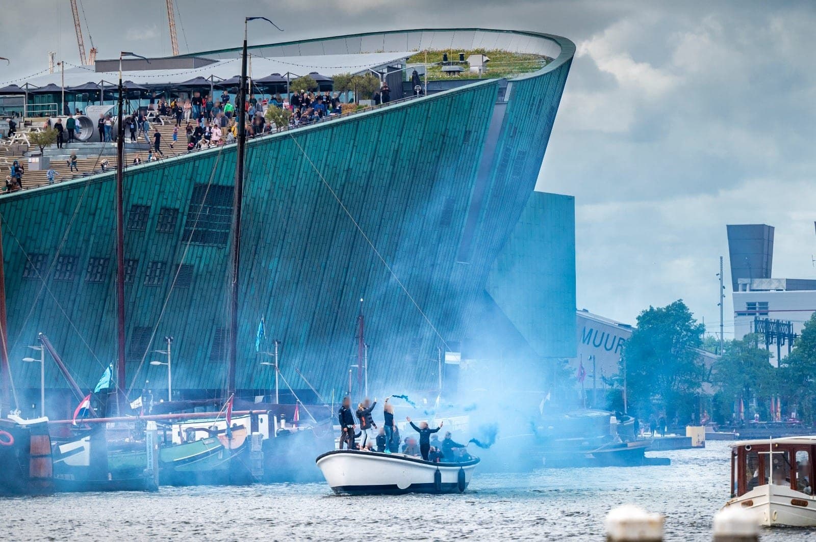 De witte sloep met blauwe rook voor NEMO in Amsterdam, bij de huldiging van de olympische watersporters